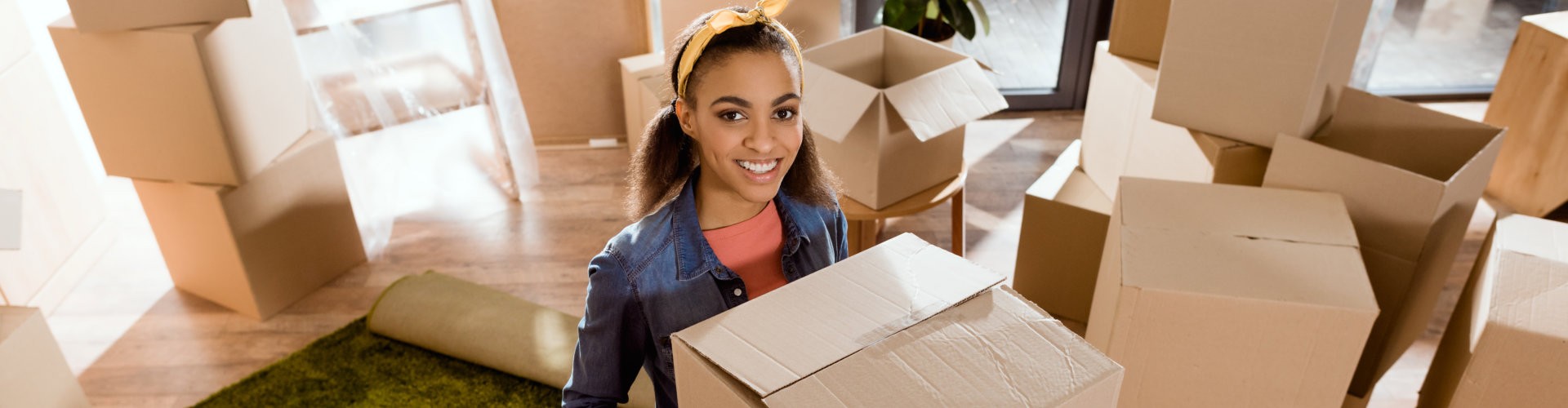 girl holding cardboard box and moving into new home